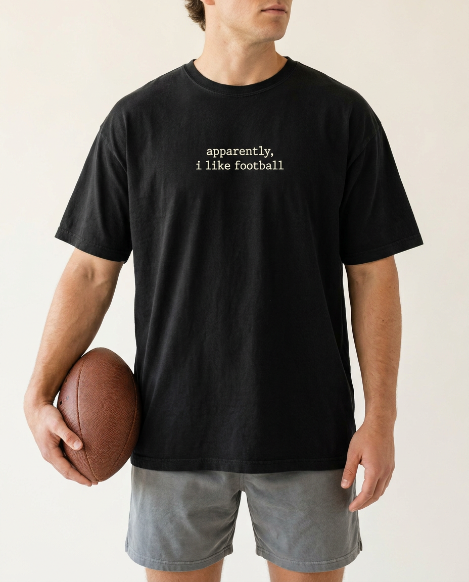 Man in black apparently i like football tee holding a football