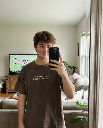 Man wearing apparently i like football tee watching the game