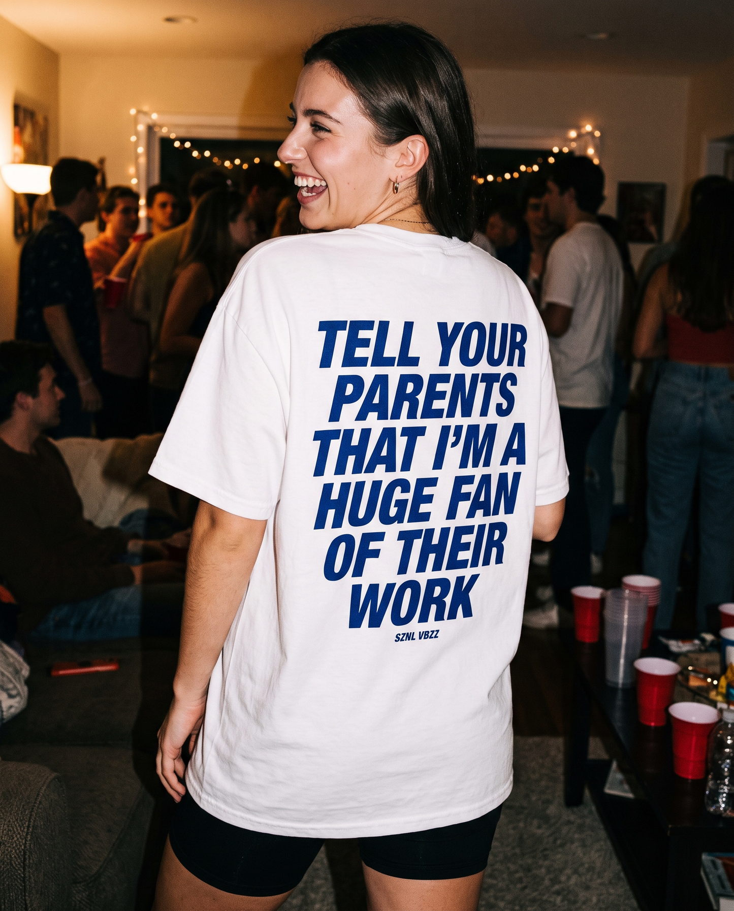 Woman wearing the oversized Tell Your Parents tee at a house party